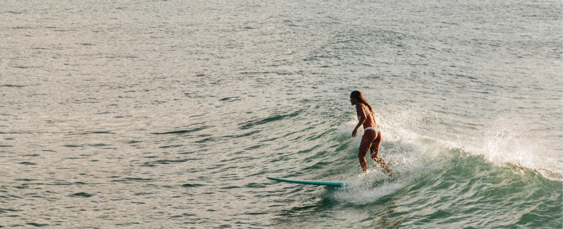 Frau surft gut weil sie Surf Fitnesstraining gemacht hat